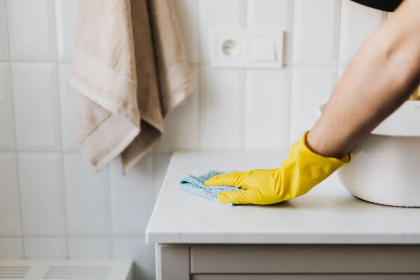 Gloved professional wiping a bathroom counter during a detailed clean